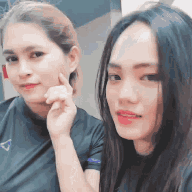 two women are posing for a picture and one has her hand on her chin