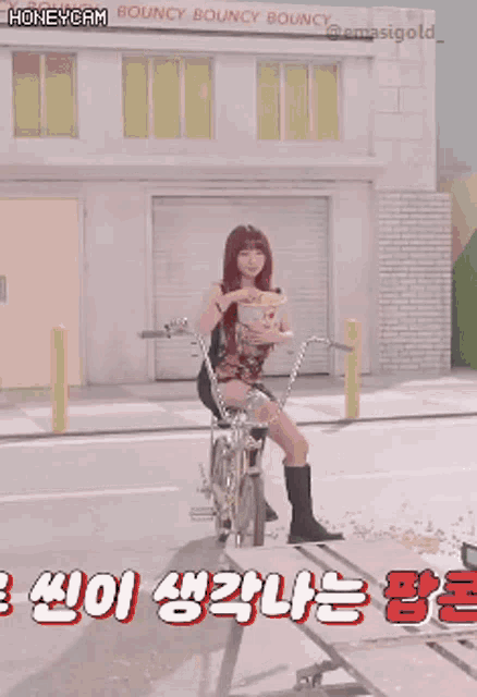 a woman is riding a bike in front of a building that says honeycam