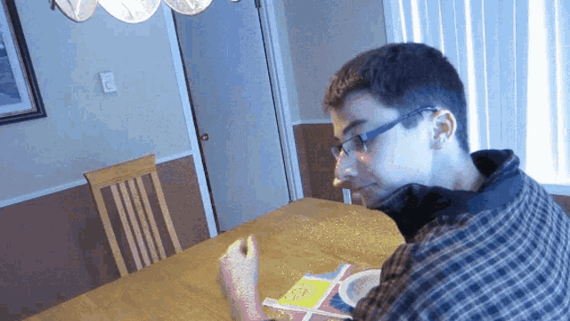 a man wearing glasses sits at a table with a book that says ' i 'm sorry ' on it