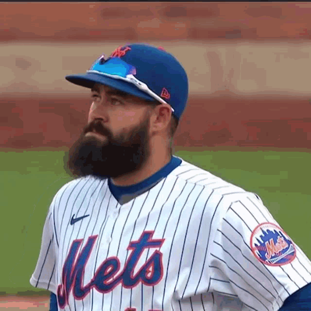 a mets baseball player with a beard wearing a blue hat and sunglasses