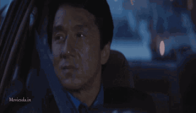 a man sitting in a car with the words moviesda.in on the bottom
