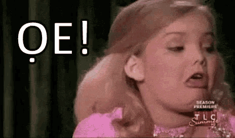 a little girl in a pink dress is making a funny face and says oe !