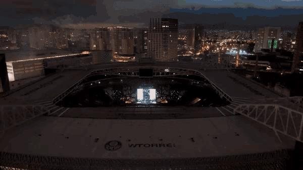 an aerial view of a stadium at night with a large screen that says ' aoa ' on it