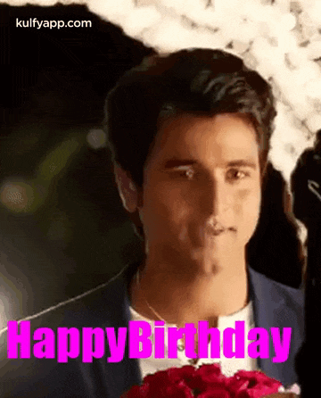a man in a suit is holding a bouquet of roses and says happy birthday .