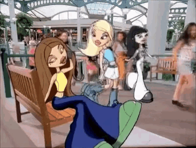 a group of bratz dolls are sitting on a park bench