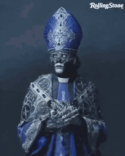 a man dressed as a priest with a mask on his face is holding a cross in his hands .