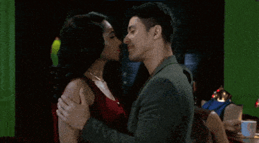 a man and a woman are looking at each other in a dark room