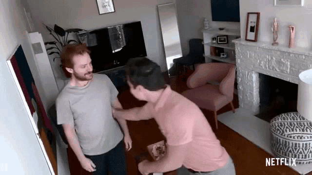 two men are fighting in a living room with a netflix logo on the corner .