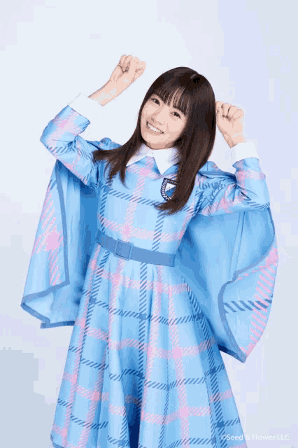 a woman wearing a blue and pink plaid dress with seed & flower llc written on the bottom