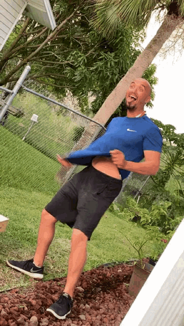 a man wearing a blue nike shirt and black shorts is laughing
