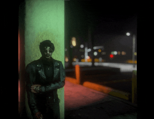 a man in a leather jacket leans against a wall