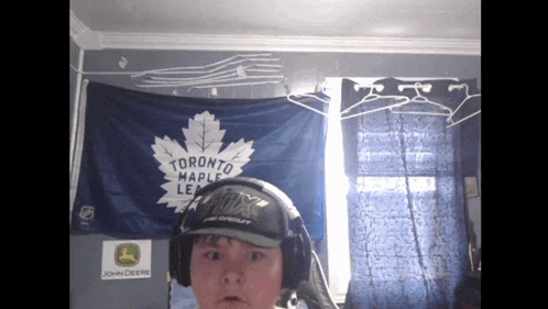a man wearing headphones stands in front of a toronto maple leafs flag