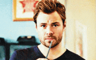 a man with a beard is holding a pen to his mouth and looking at the camera .