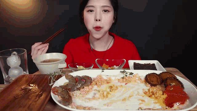 a woman in a red shirt is eating a plate of food