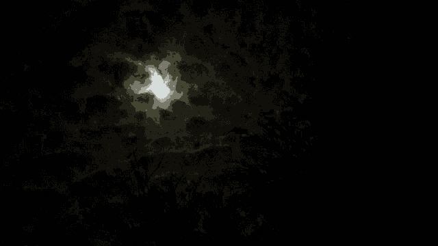 a full moon shines through the clouds in a dark night sky