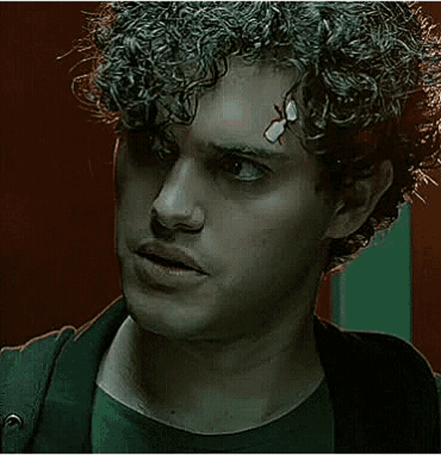a young man with curly hair and a bandage on his forehead .