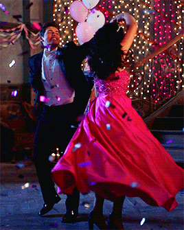 a man in a tuxedo and a woman in a pink dress are dancing together