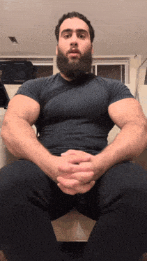 a man with a beard is sitting with his legs crossed