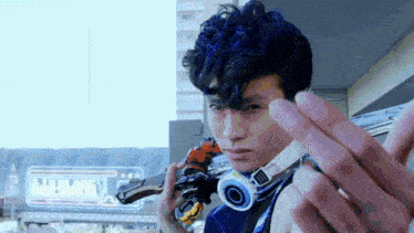 a young man with blue hair and headphones is holding a gun and making a funny face .