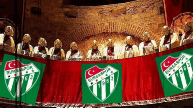 a group of people sitting on a stage with bursaspor logos on them