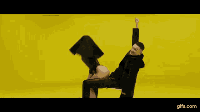 a man is holding a woman 's leg in a high heeled shoe on a yellow background .