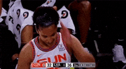 a basketball player in a sun jersey is sitting in the stands during a game .