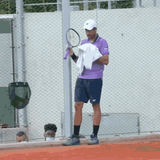 a man in a purple shirt holding a tennis racquet
