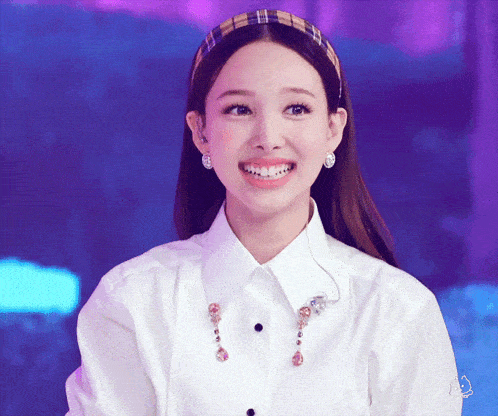 a woman wearing a plaid headband and earrings is smiling