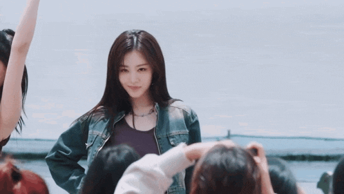 a woman in a denim jacket is standing in front of a group of people