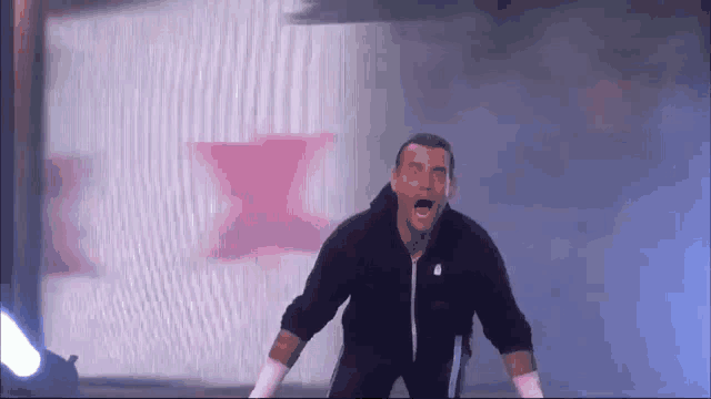 a man in a black jacket is standing on a stage with his mouth open and his arms outstretched .