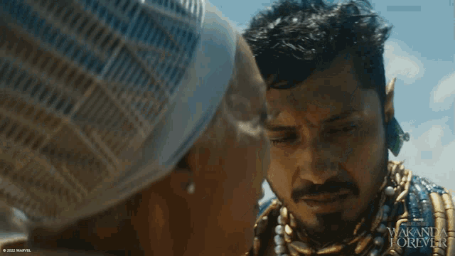 a man and a woman are looking at each other with the words wakanda forever on the bottom right