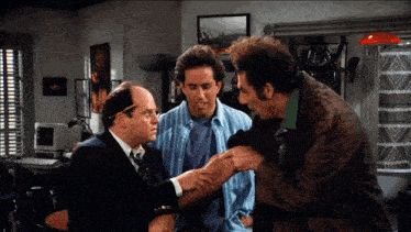 three men are standing in a room and one of them is holding the arm of another man