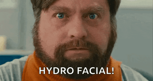 a man with a beard is saying `` hydro facial '' while looking at the camera .