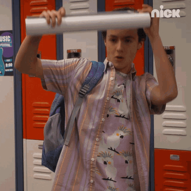 a boy in a purple shirt is holding a roll of paper in front of lockers with a poster that says music festival on it