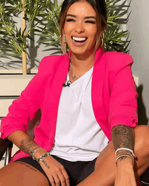 a woman wearing a pink blazer and a white shirt has a tattoo on her wrist that says ' i love you '