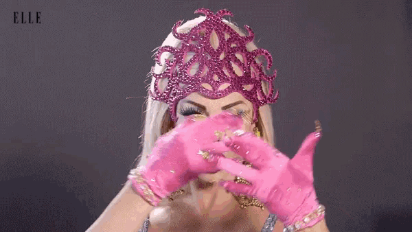 a woman wearing a pink headpiece and pink gloves has the word elle on the bottom right