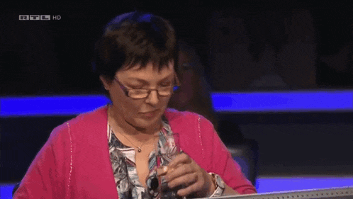 a woman wearing glasses and a pink sweater is on a television show