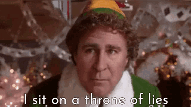 a man in a santa hat is sitting on a throne of lies in front of a christmas tree .