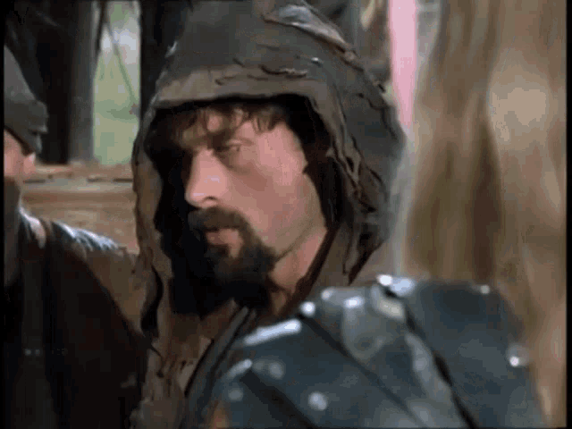 a man with a beard is wearing a hooded cape