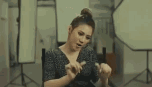 a woman in a black dress is sitting in a chair in front of a camera in a studio .