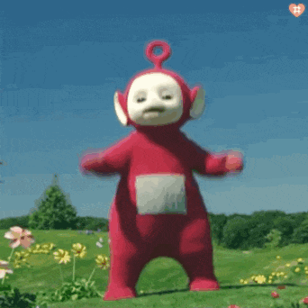 a red teletubbies teddy bear is jumping in the air in a field .