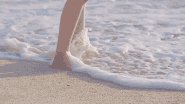 a woman 's feet are splashing in the ocean