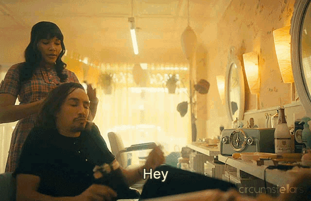 a man is getting his hair cut by a woman and the words hey are visible