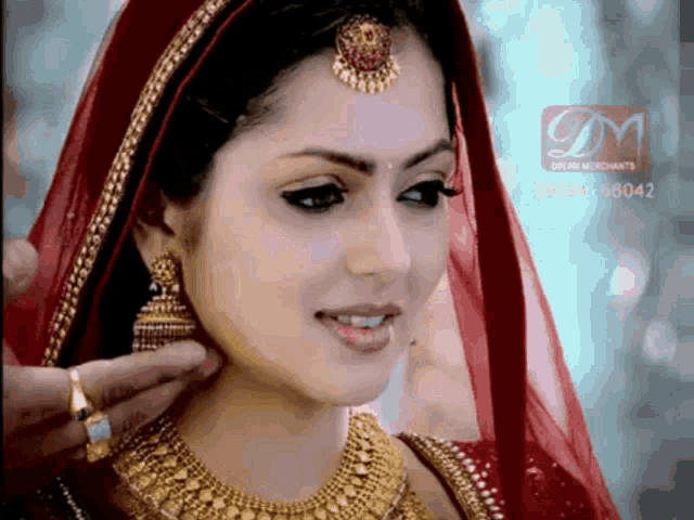 a woman wearing a red veil and gold jewelry has a dream merchants logo on the bottom
