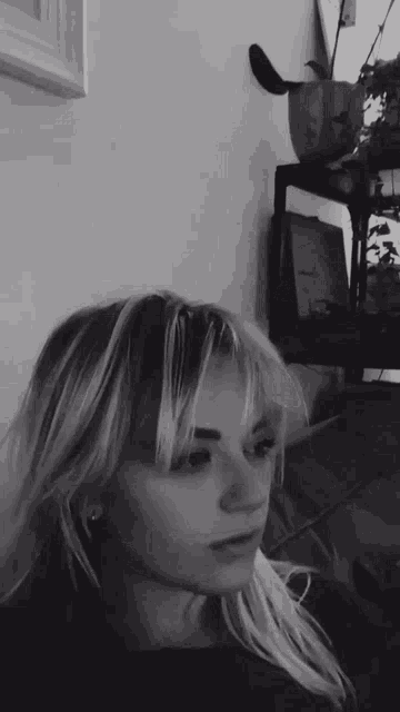 a woman 's face is shown in a black and white photo with a plant in the background