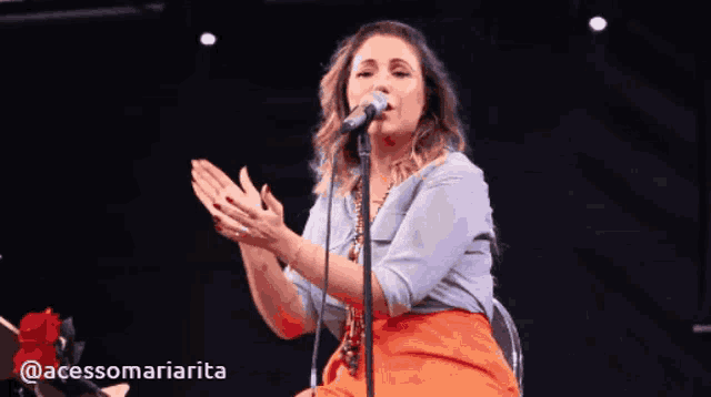 a woman singing into a microphone with the hashtag @acessomaniarita
