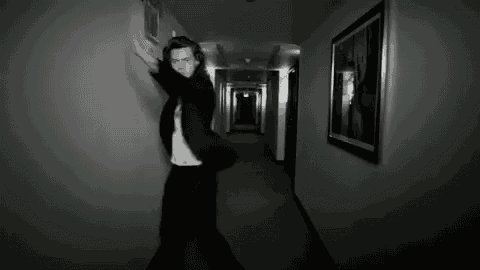 a black and white photo of a man in a suit dancing in a hallway