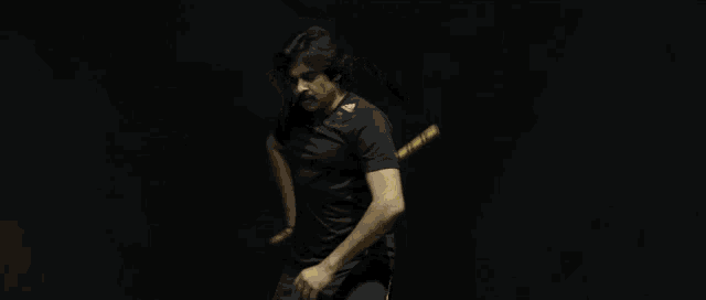 a man in a black shirt is holding a yellow stick in his hand