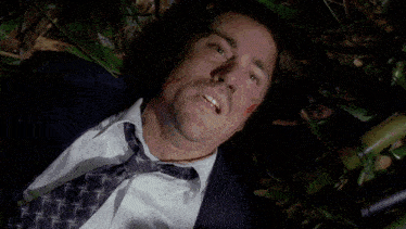 a man in a blue shirt is laying on the ground with a dog