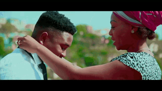 a woman adjusts a man 's tie while he looks at her